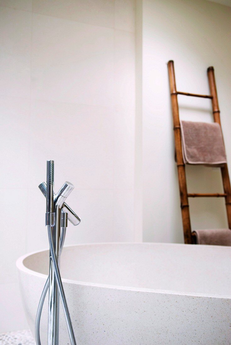 Bathroom with free-standing bathtub, floor-mounted tap fittings and ladder as towel rack
