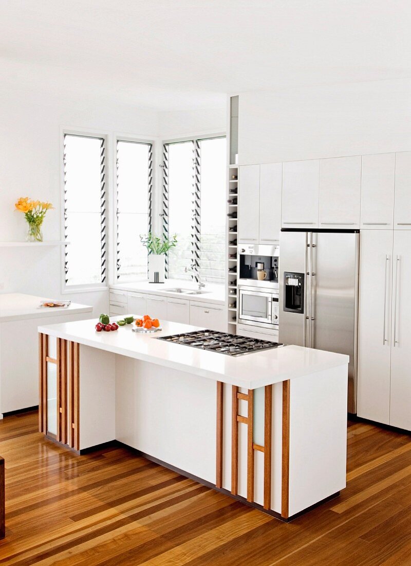White fitted kitchen with stainless steel appliances and island counter