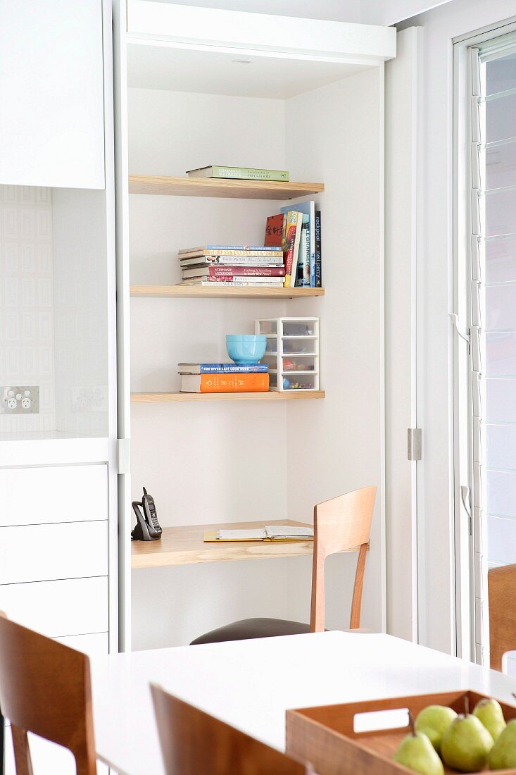 Dining table in front of fitted shelving with integrated desk