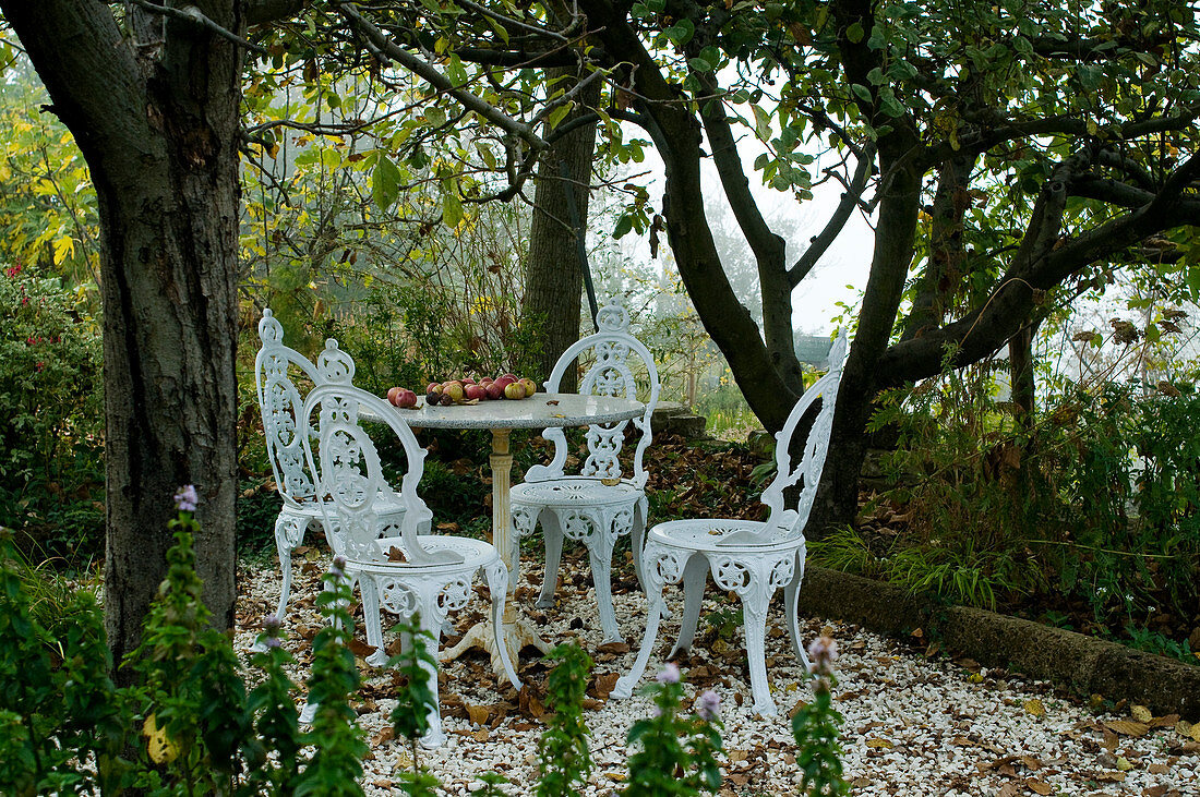 Gartenplätzchen mit Tisch und Stühlen aus weiss lackiertem Metall im Vintagestil