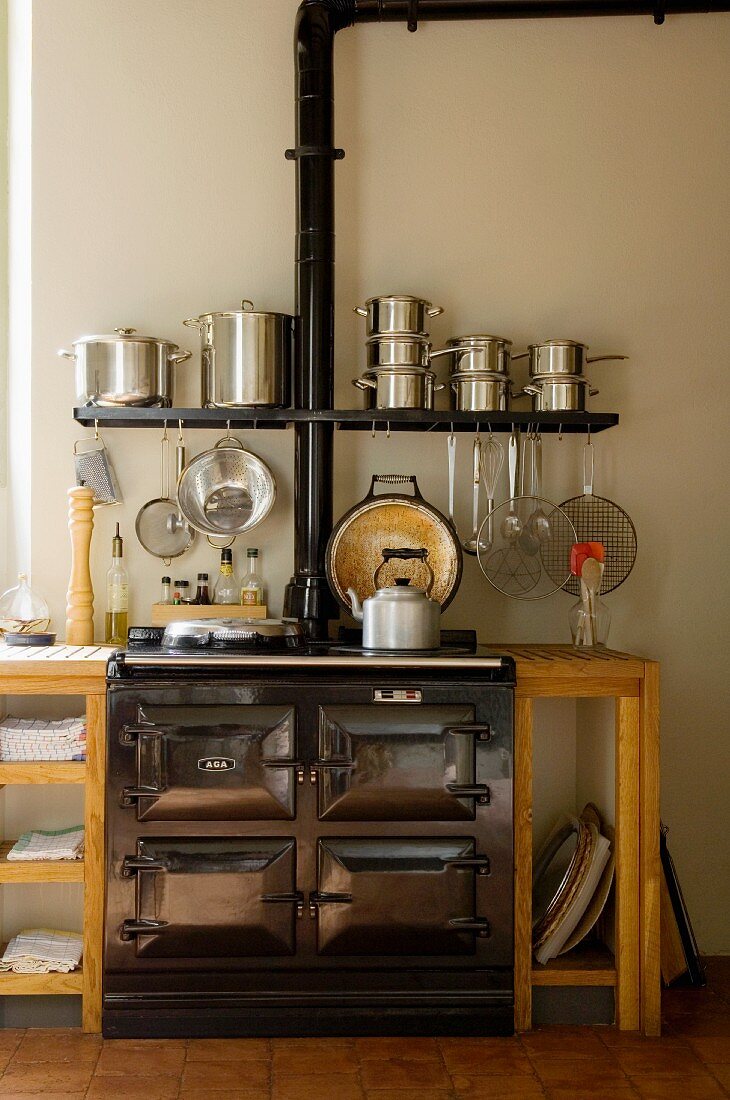 Vintage Küchenofen in schlichter Küchenzeile mit integriertem Wandbord und gestapelten Edelstahltöpfen