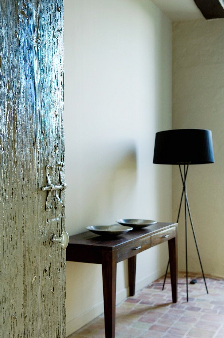 Offene Zimmertür mit Blick auf schlichten Wandtisch neben Designer Stehlampe