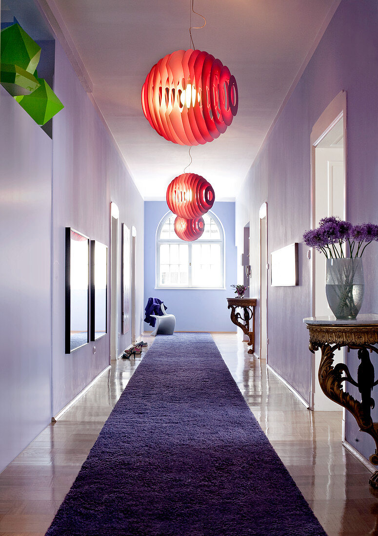 Three red Foscarini pendant lamps and antique console tables in lilac, eclectic ambiance of long period hallway