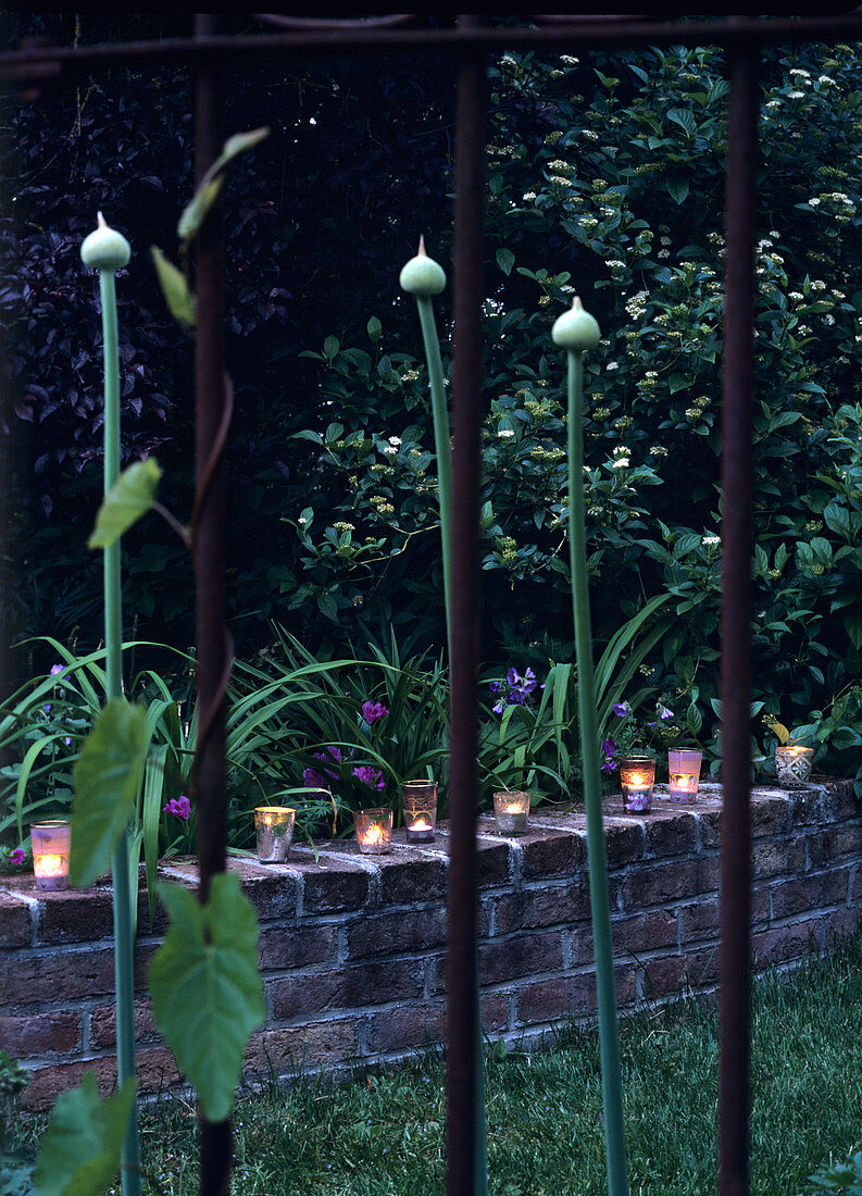 Decorative candle lanterns on small brick wall in garden
