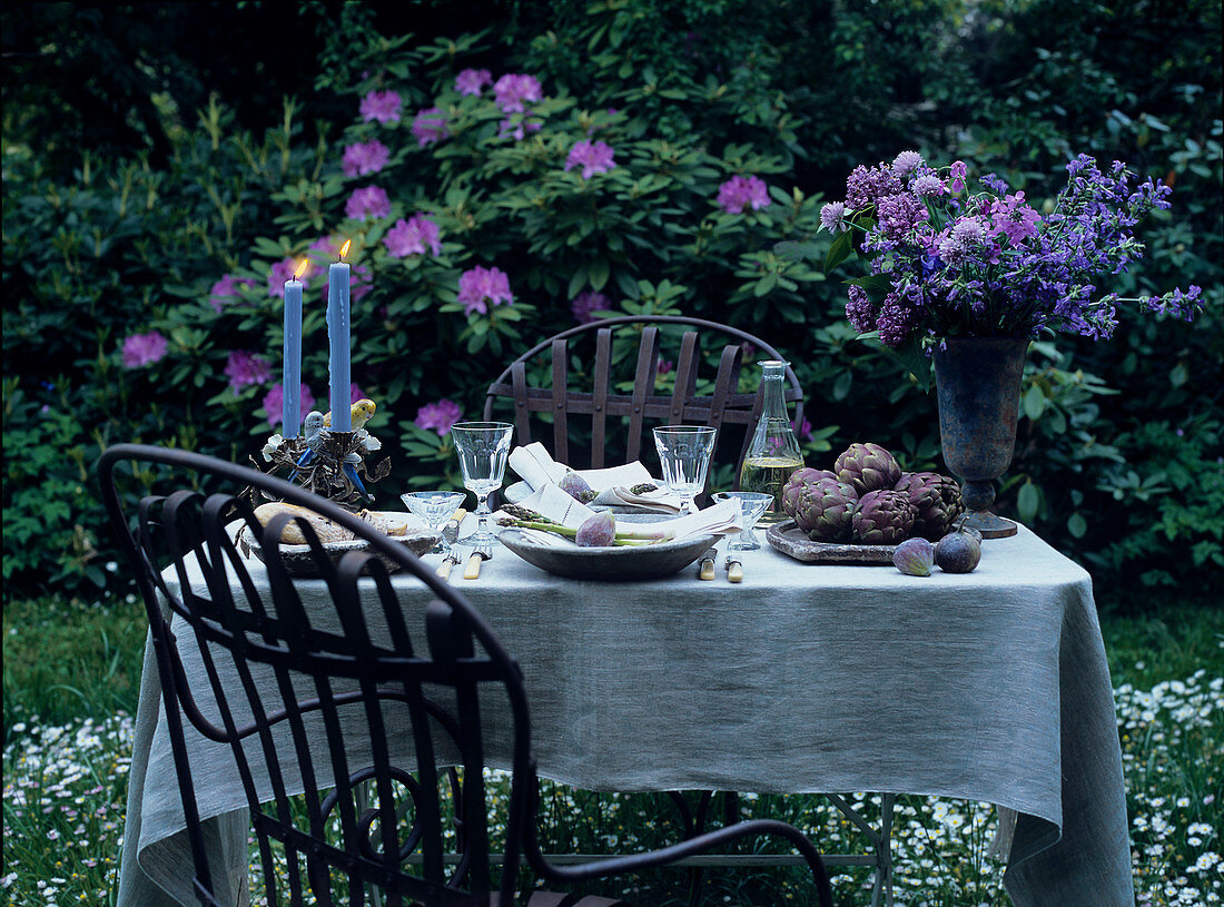 Romantisch gedeckter Tisch mit Kerzen und Blumen im Garten