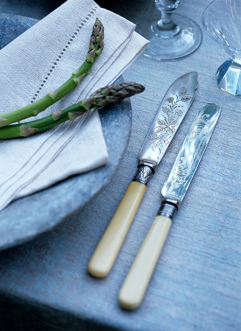 Antike Messer mit Elfenbeingriffen neben Steinteller mit Spargeldeko