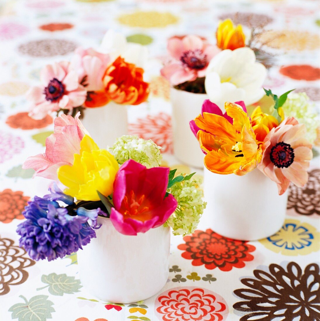 Bunte Blumensträusse auf Tischdecke mit Blumenmuster
