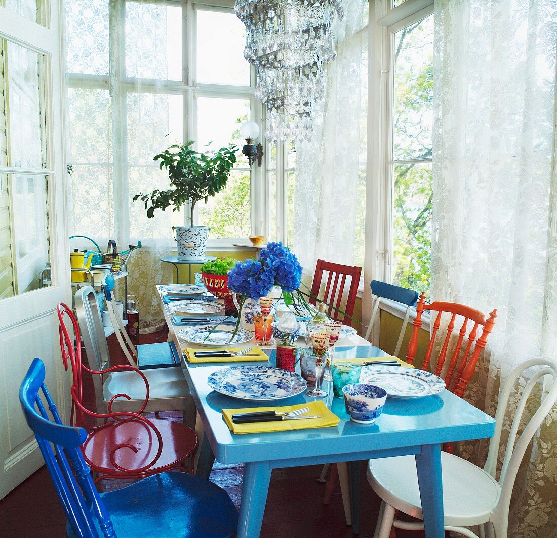 Colorful kitchen chairs in mix of styles around a set dining table