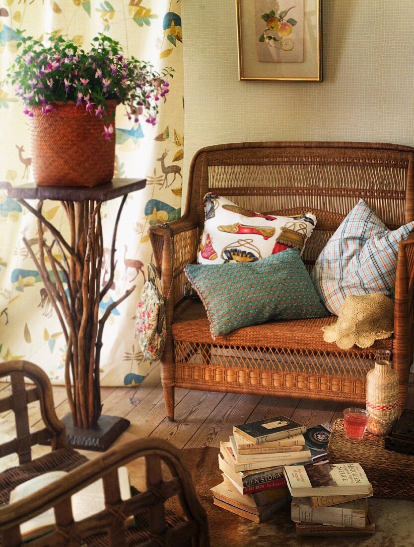 Cozy wicker chair with pillows next to a potted plant on a pedestal