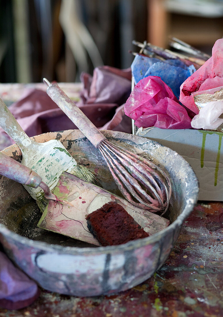 Painters' utensils in paint-spattered bowl