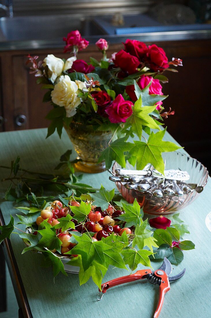 Cherries, a bunch of roses and cutlery on a kitchen table