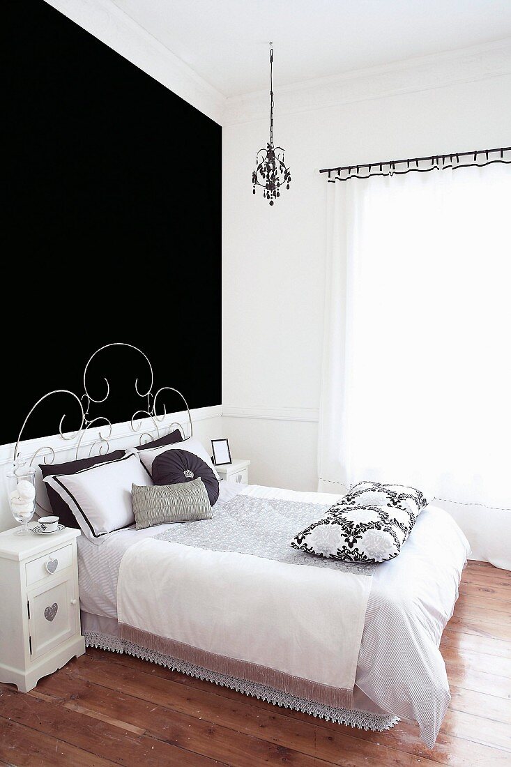 Bed with delicate metal frame against black-painted wall in modern bedroom