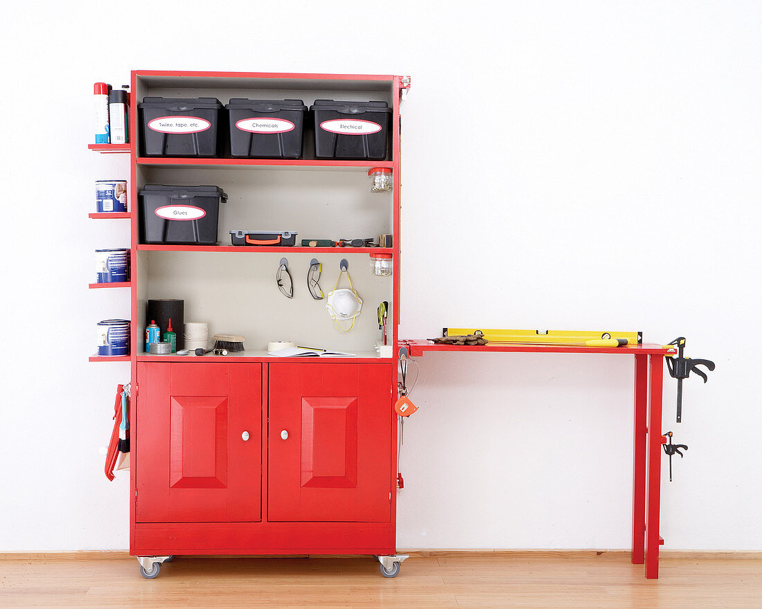 Der umgebaute Küchenschrank in Rot auf Rollen mit integriertem Arbeitstisch dient zur Werkzeugaufbewahrung