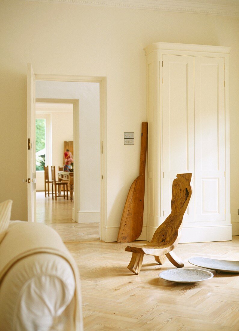 Selbstgebautes Stuhlobjekt neben Schalen auf Boden im puristischen, hellen Wohnraum