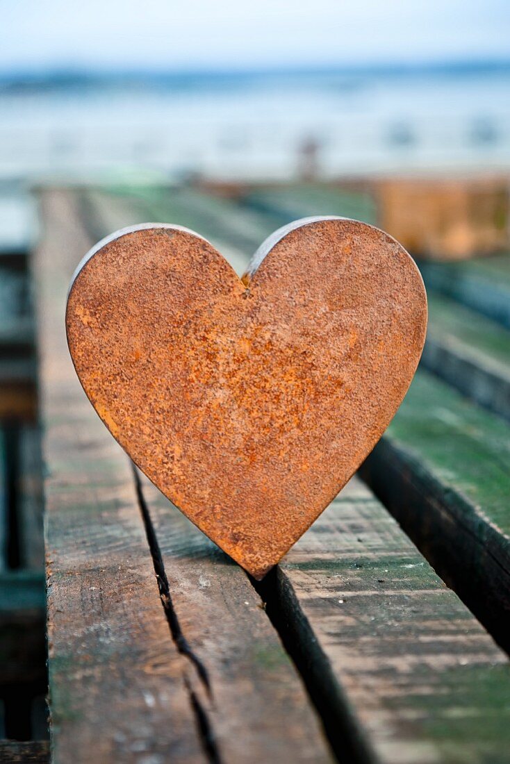 Rusty metal heart on wooden boards