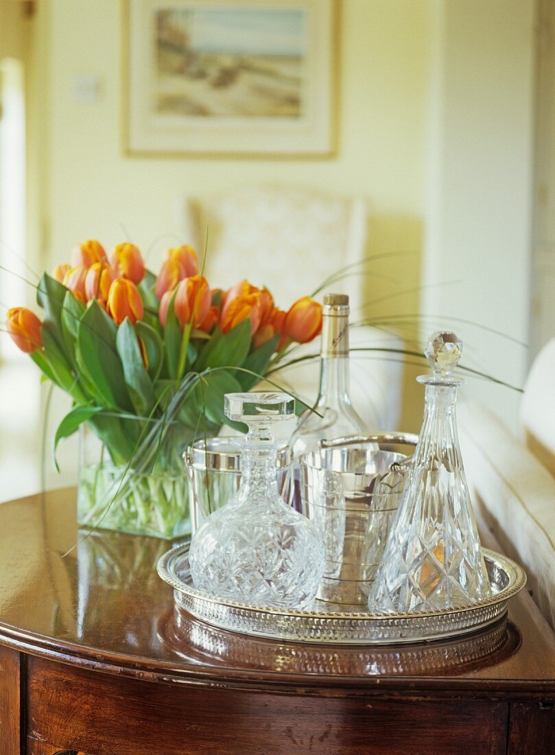 Crystal decanters on silver tray next to bouquet of orange tulips