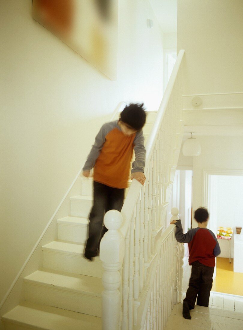 Children on white-painted, wooden staircase with turned balusters