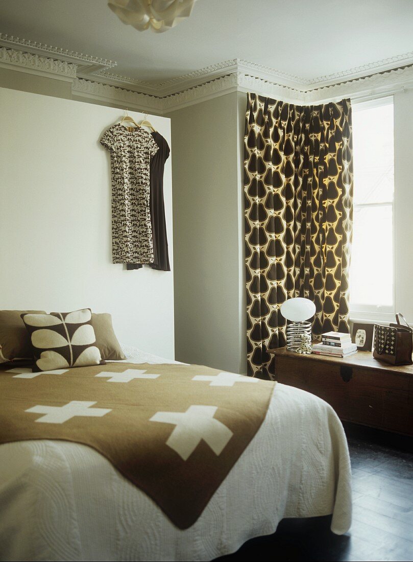Brown and white throw on double bed and curtain on window
