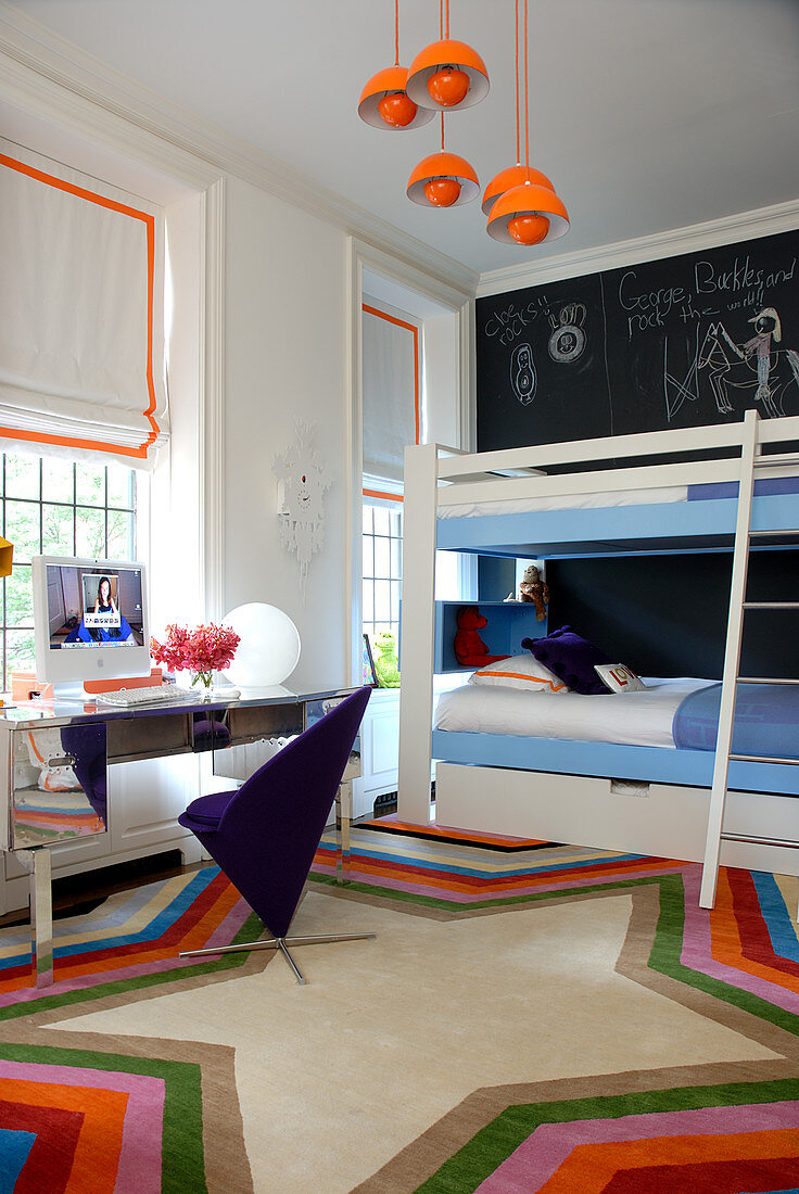 Kinderzimmer mit Etagenbett, leuchtend orangen Akzenten und einer schwarzen Wand als Tafel