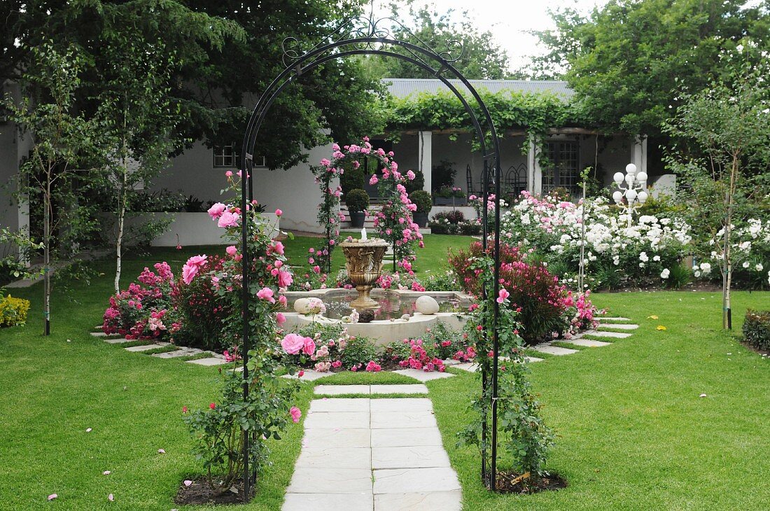 Liebevoll angelegter Rosengarten mit Gartenbogen, Springbrunnen und Rasenfläche