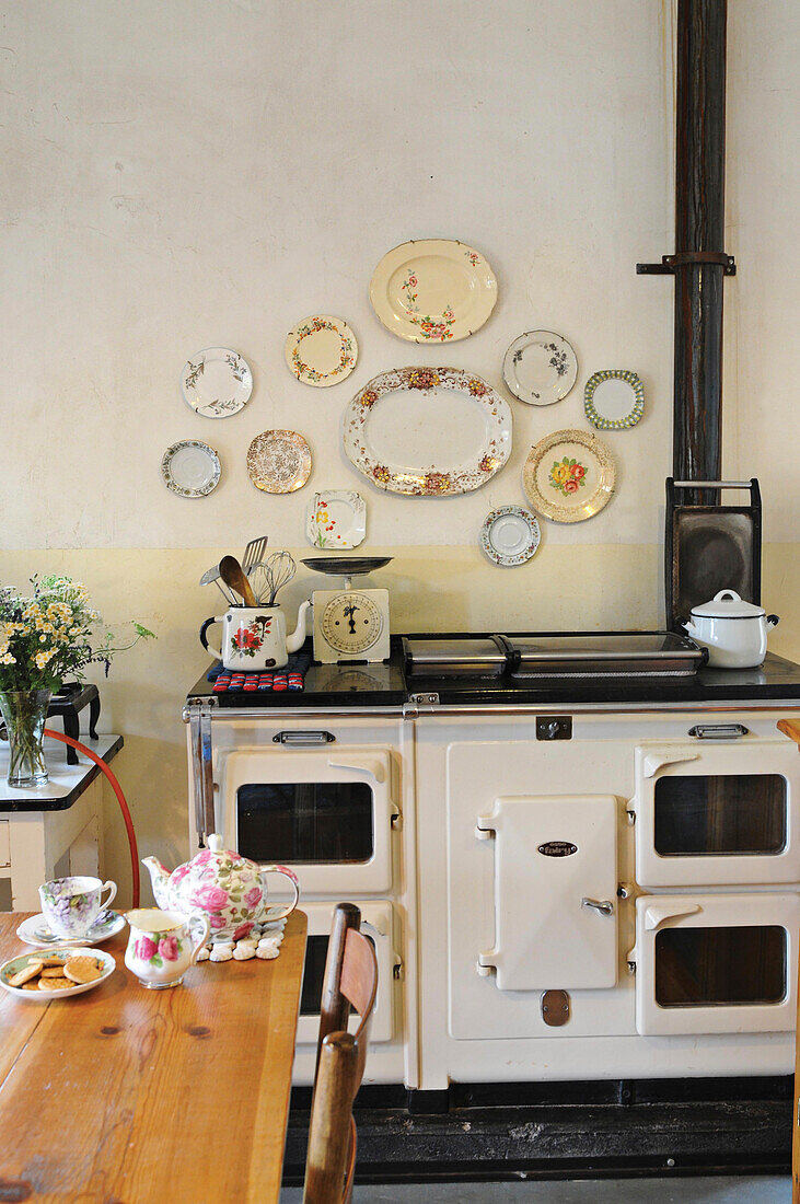 Decorative wall plates above old wood-burning cooker in kitchen