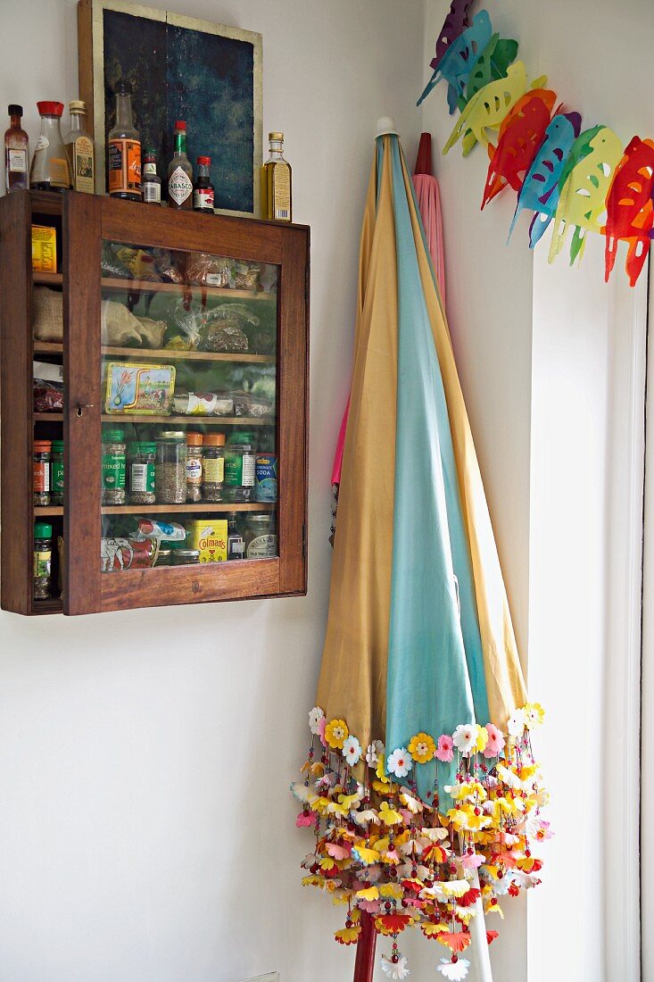 Colourful parasols and spice cabinet on wall in corner of kitchen