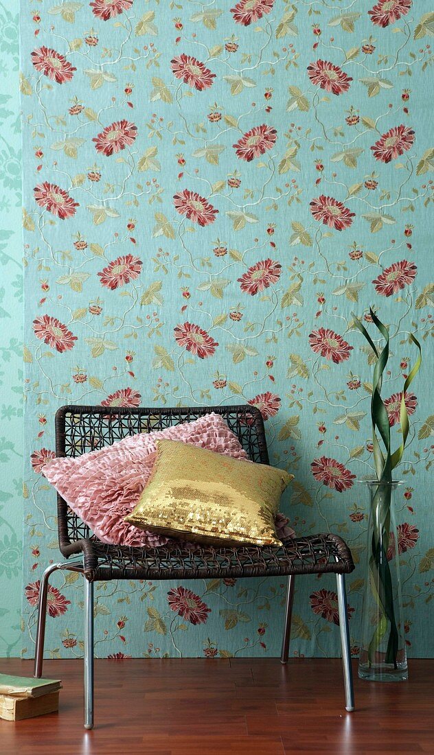 Low chair and decorative pillows in front of floral wallpaper