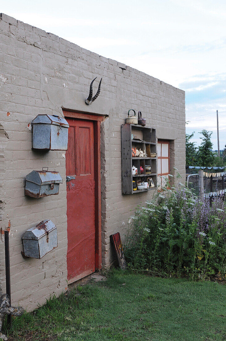 Old letterboxes and shelves of crockery on exterior house wall