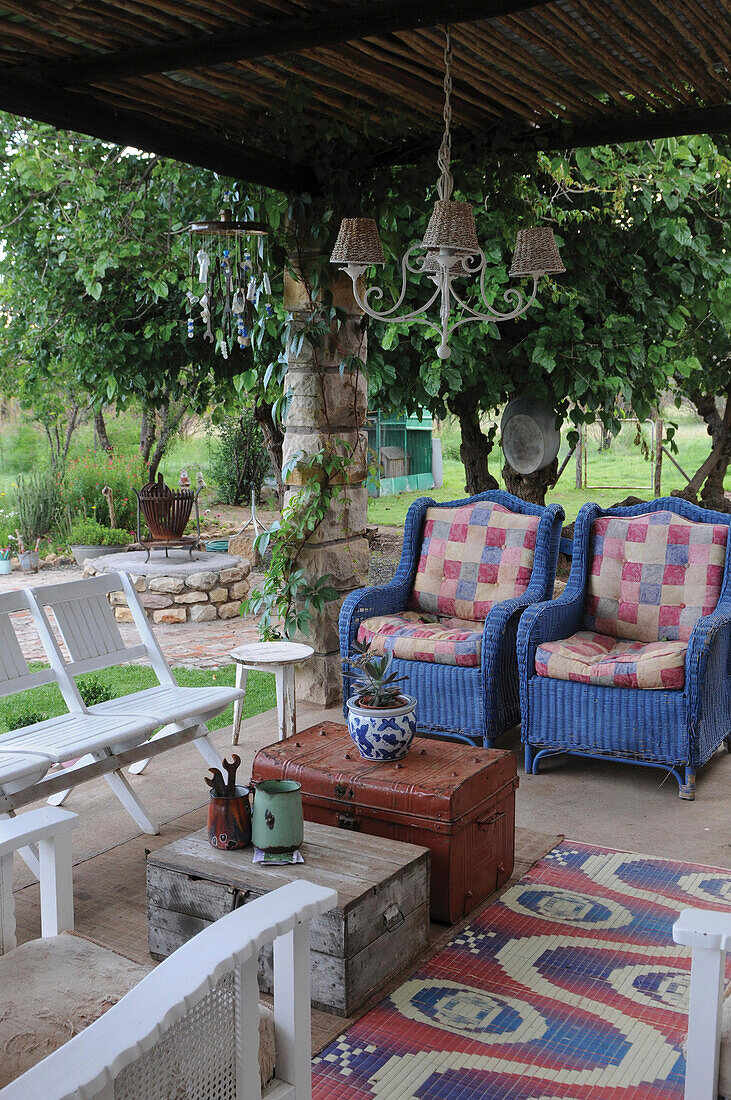 Two basket chairs on roofed terrace and two old trunks serving as a table