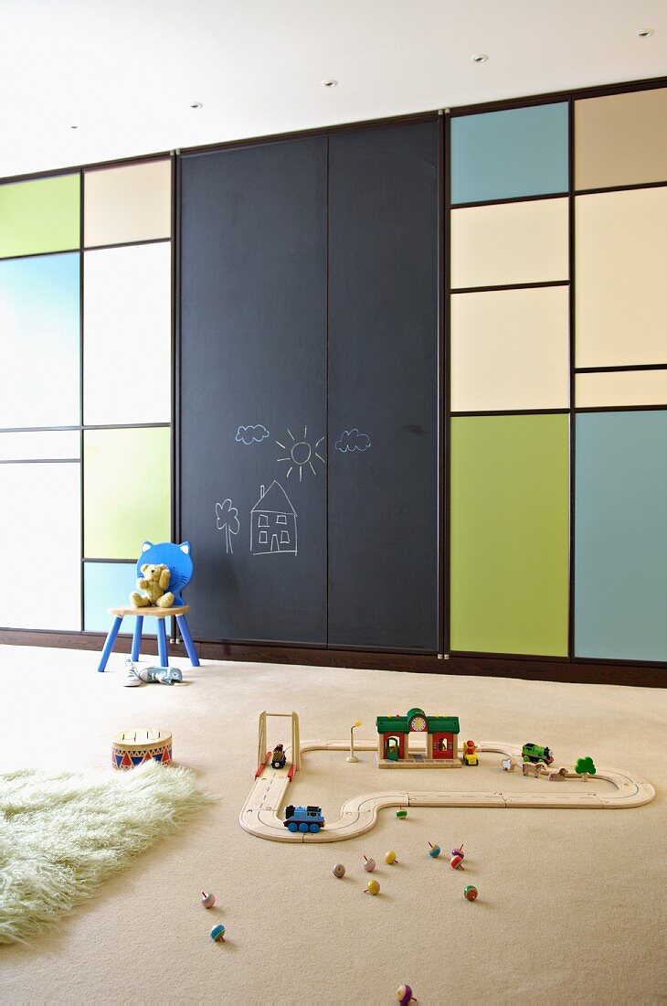 Child's bedroom with model railway in front of fitted wardrobes with Mondrian-style doors