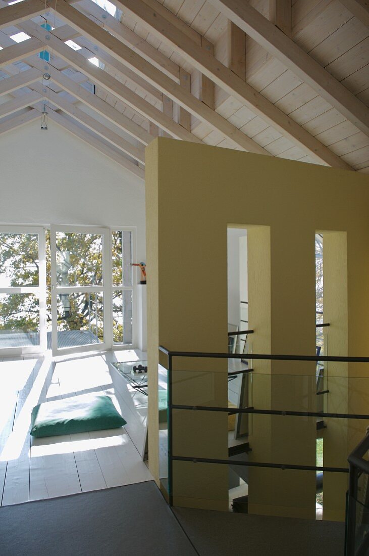Offener Dachraum mit weiss lackierter Holzdecke und Balkontür