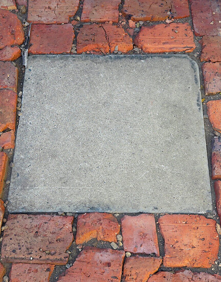 Square concrete block combined with uneven brick pavement