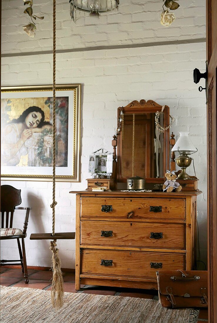 Antique wooden chest of drawers with a mirror in front of a brick wall