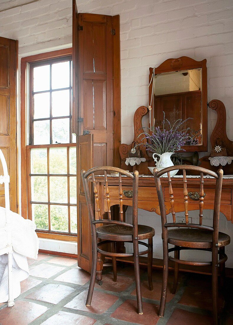 Antiker Kosmetiktisch und Holzstühle in rustikales Schlafzimmer