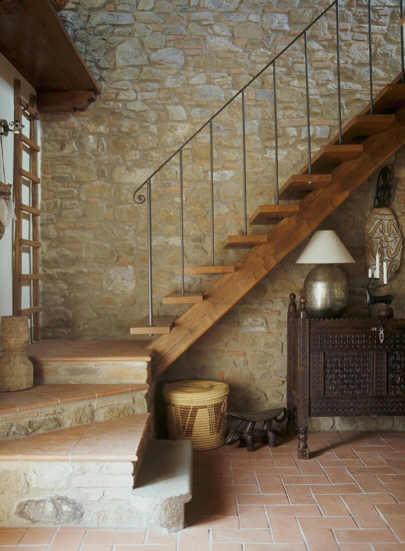 Holztreppe vor Natursteinwand im Vorraum eines Rustikos