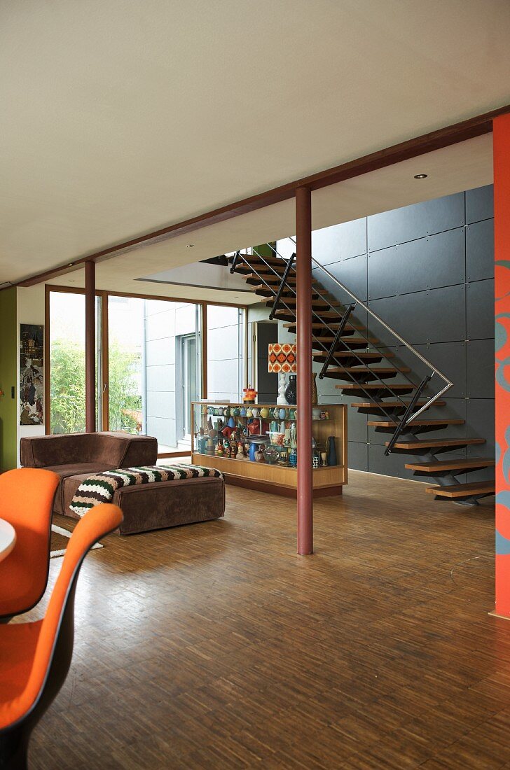 Offener Wohnraum mit Sofa und Theke vor Treppenaufgang