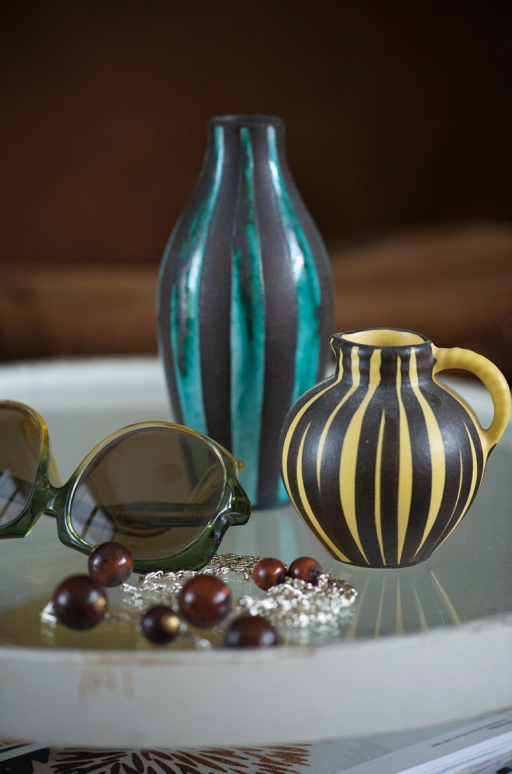 Verschiedene Vasen im Zebralook neben Sonnenbrille auf Tablett