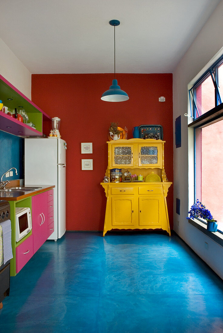 Alte gelb gestrichene Anrichte in der Küche mit blauem Zementboden