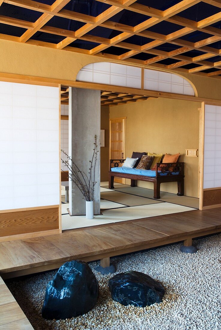 Vorraum mit Podest und Kiesboden vor offenem Wohnraum in japanischem Stil