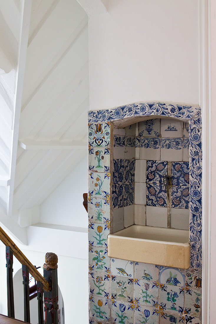 Treppenraum mit farbigem antikem Holzgeländer und altes Waschbecken in Mauernische mit historischen Delfter Fliesen