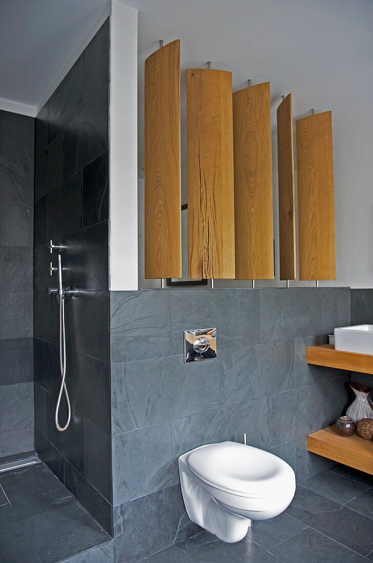 Rotatable wooden screen panels in modern bathroom with slate tiles