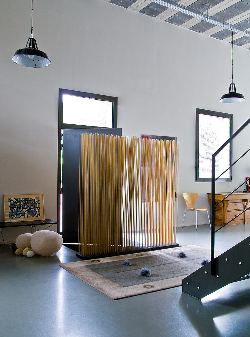 Künstlerisch gestalteter Windfang aus Holzstäben vor Haustür in loftartigem Wohnraum