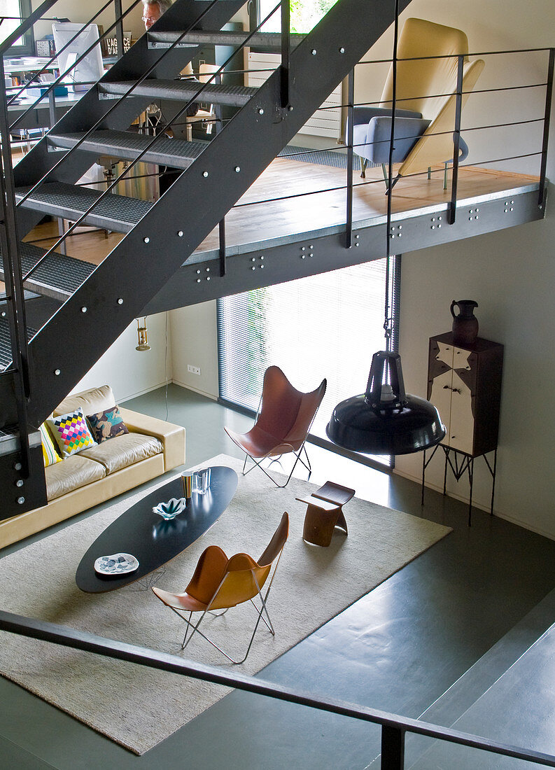 Blick von Galerie in minimalistischen Wohnraum auf Klassiker Sesseln und Couchtisch