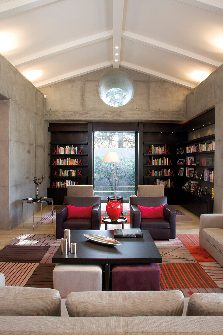 Contemporary architecture - built in shelves in the exposed concrete walls and upholstered straight line furniture with color accents