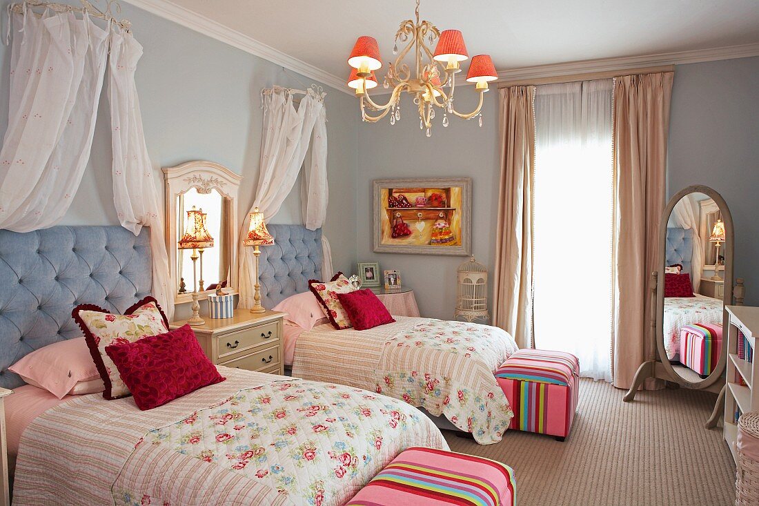 Romantisches Schlafzimmer mit Einzelbetten und einer dazwischen stehenden Spiegelkommode; Akzente in Pink sorgen für eine warme und fröhliche Atmosphäre