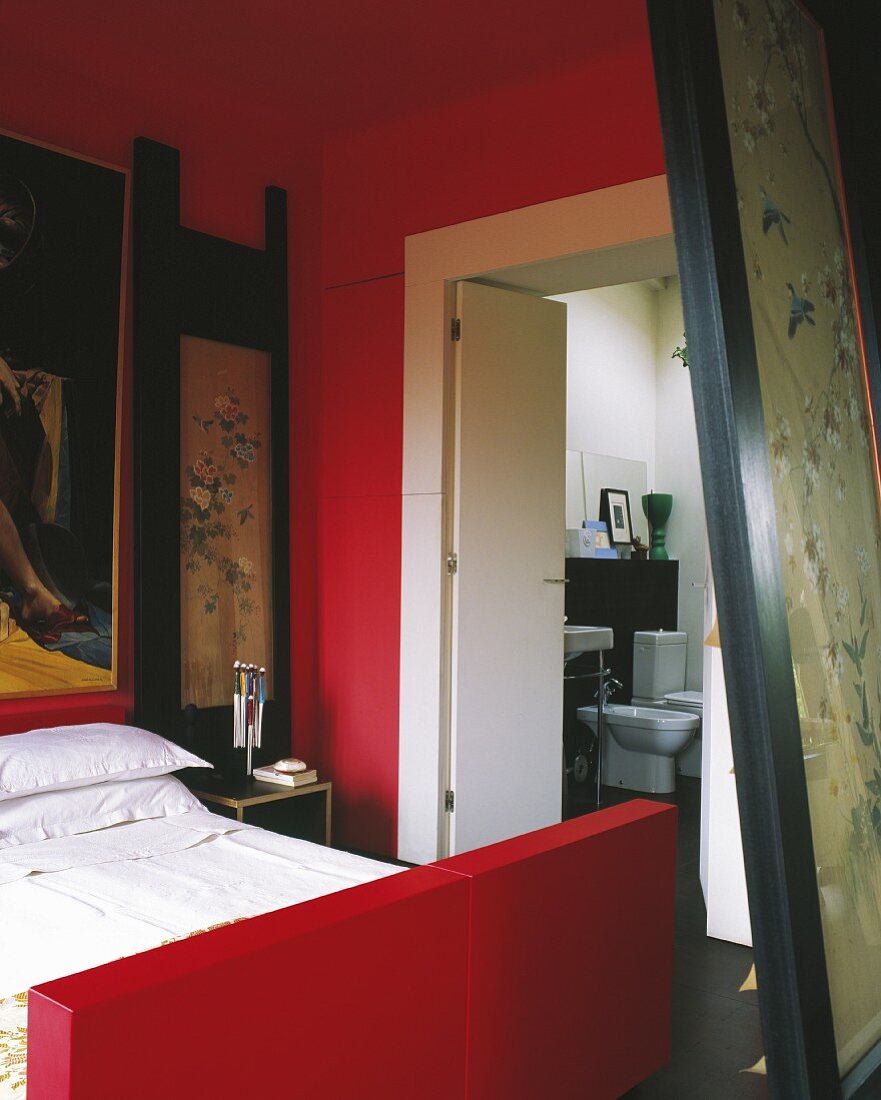 Bett mit rotem Gestell in rot getöntem Schlafzimmer mit Bad ensuite