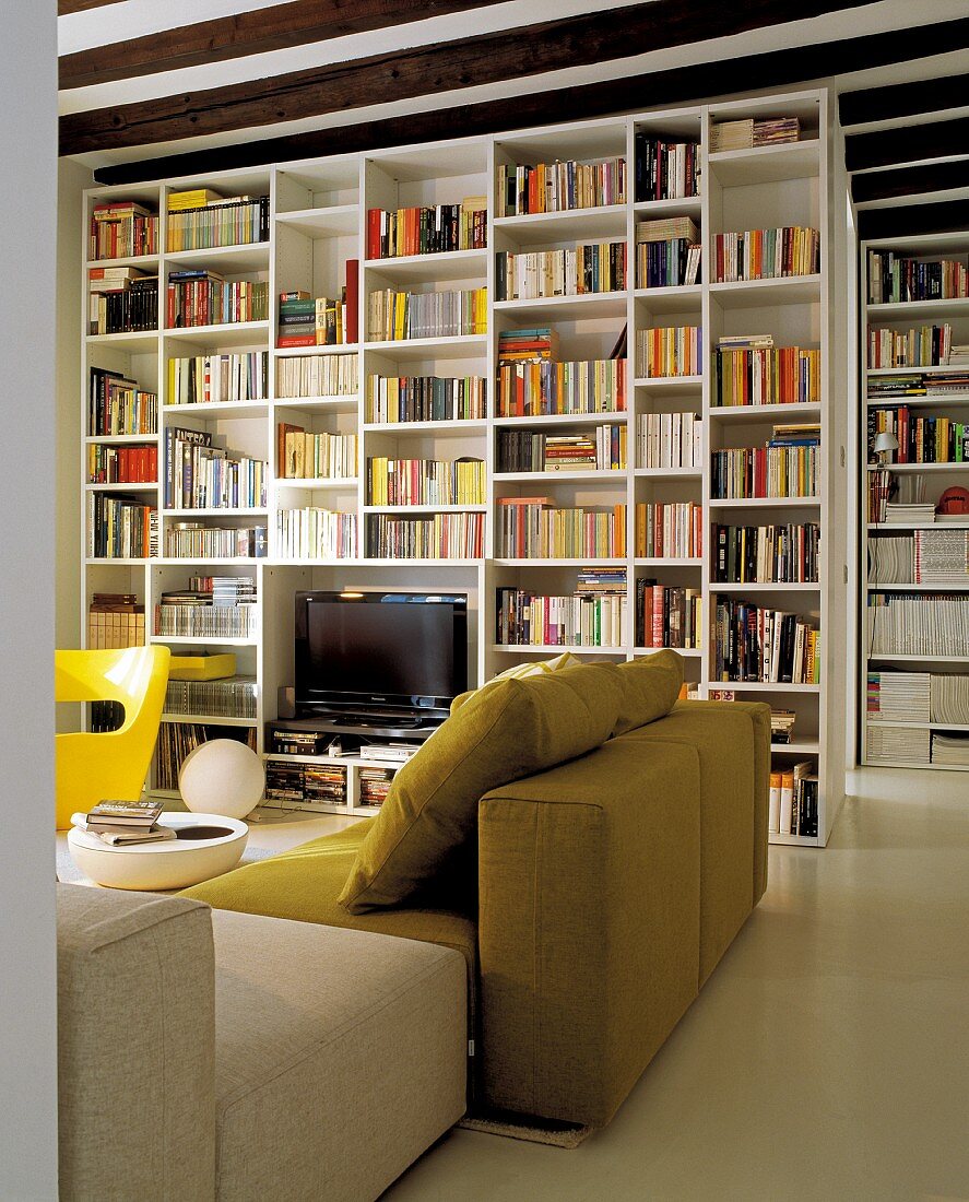 Sitzecke im modernen, italienischen Design vor großen, weissen Raumteiler-Bücherregalen