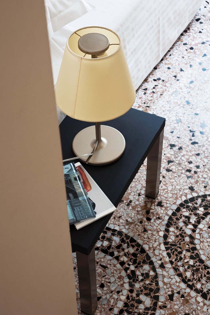 Table lamp with yellow fabric lampshade on side table on terrazzo floor