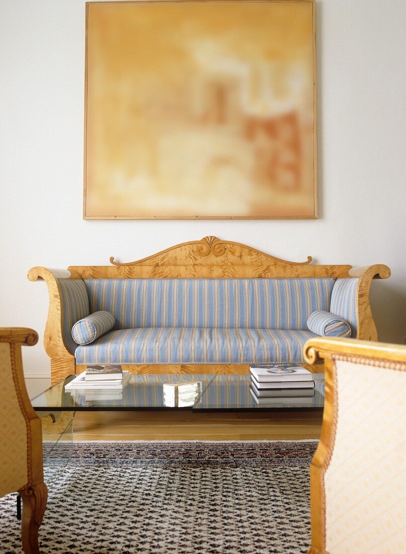 Sofa mit gestreiftem Bezug im Biedermeierstil und moderner Couchtisch mit Glasplatte