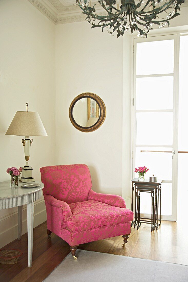 Antiker Polstersessel mit Ornamentmuster auf rosa Brokatbezug in traditioneller Zimmerecke